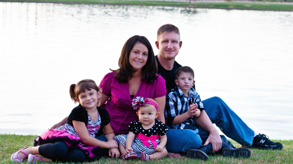 Mom Dad two daughters and a son on the grass beside a lake