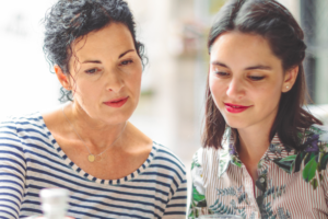 two dark haired women at an outside table