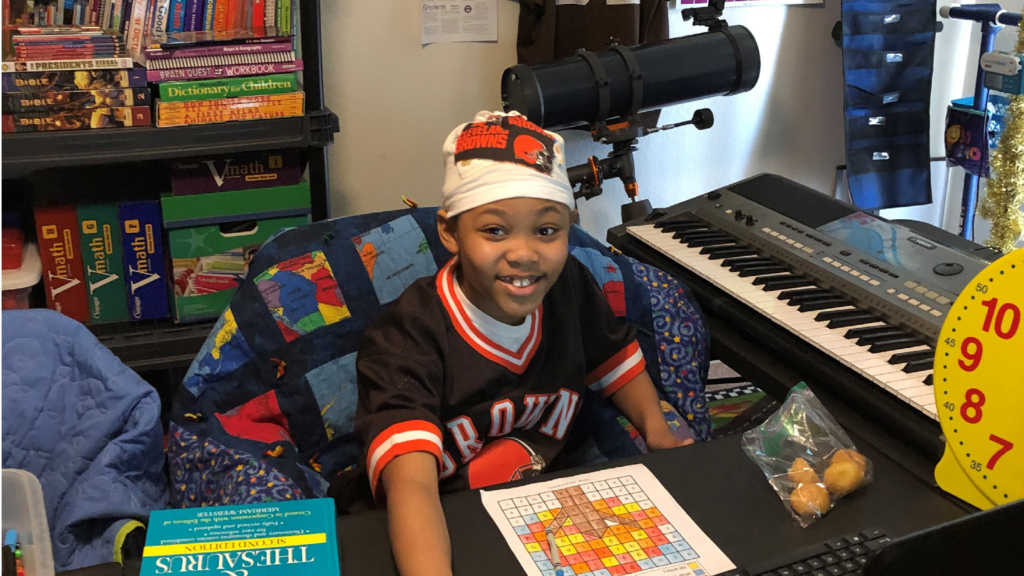 Young smiling boy in his room surrounded by books toys keyboard telescope